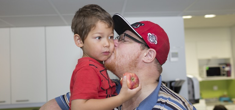 en pappa pussar sitt barn på kinden