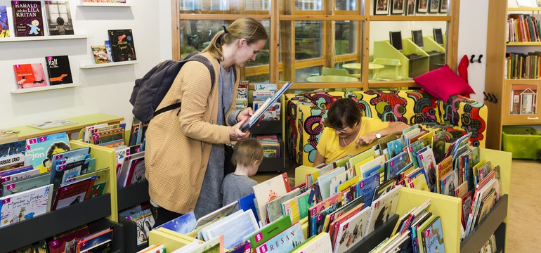 Förälder och barn i samtal med personal på ett bibliotek