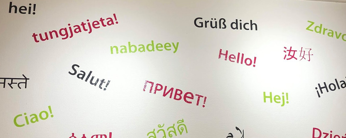Bild på en vägg där ordet "hej" står på många olika språk